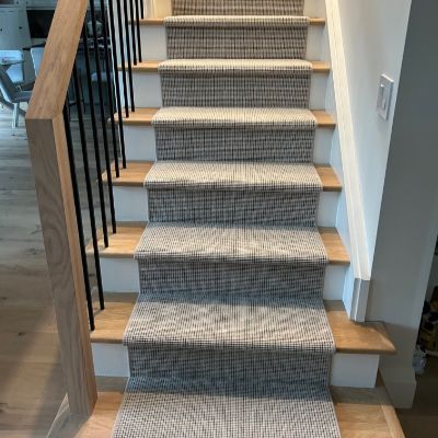 Modern staircase with gray patterned runner, oak steps, and black spindles.